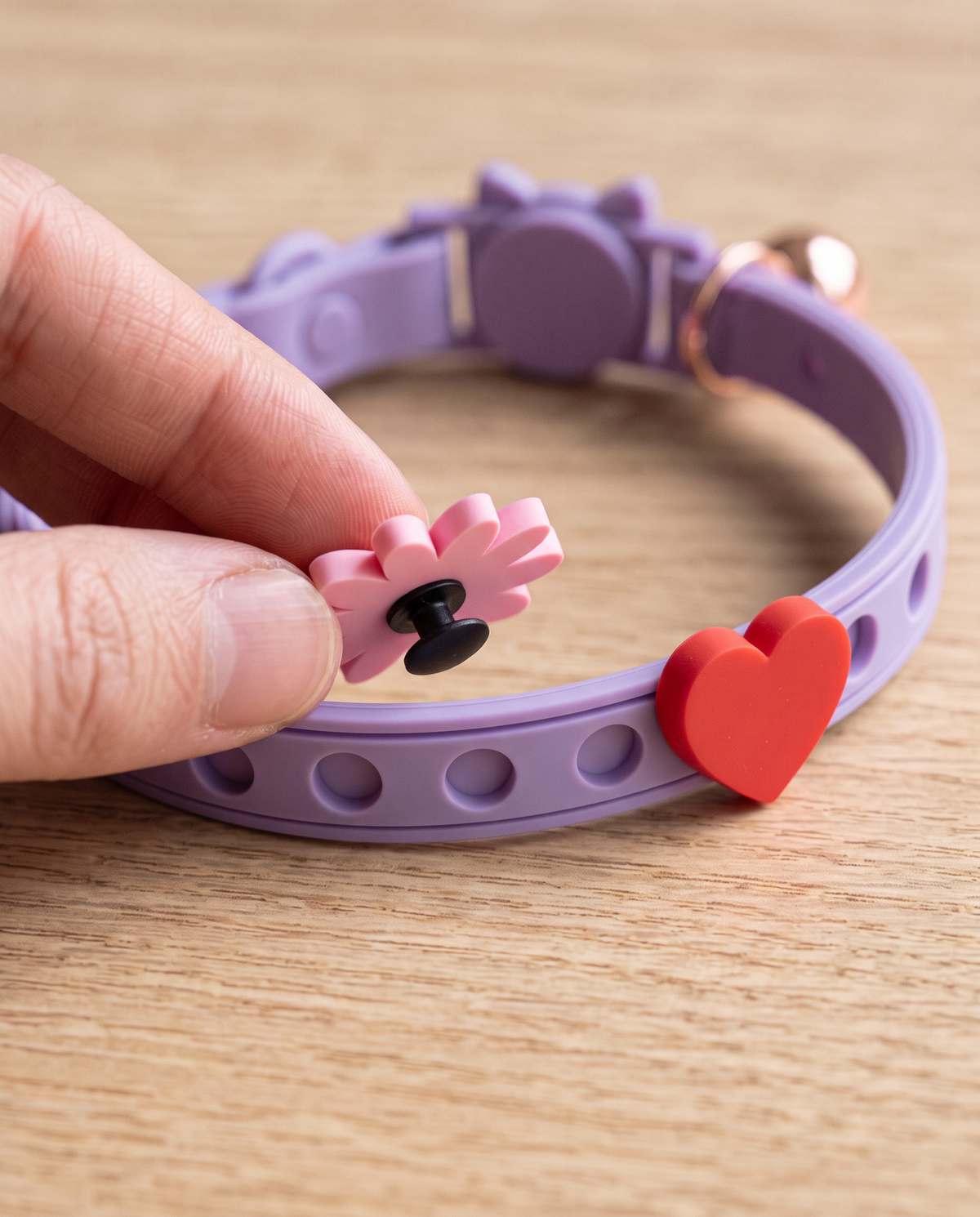Hand fitting a daisy charm into a punched hole on the lavender collar